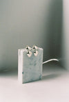 Pair of silver earrings on a white surface with a gray background