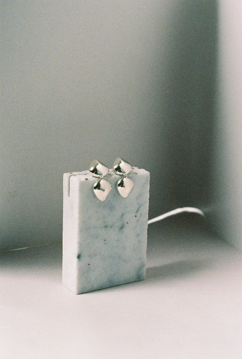 Pair of silver earrings on a white surface with a gray background